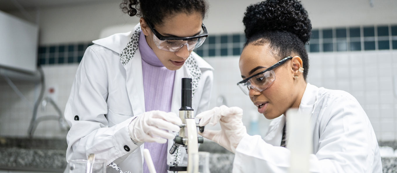 Two female students in lab with microscope